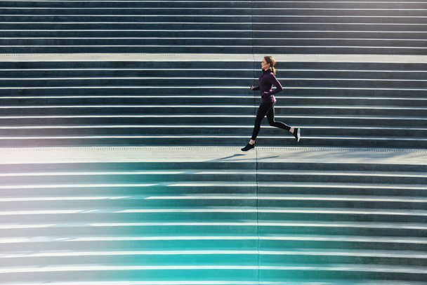 You have to work for it. Full length shot of an attractive young sportswoman running up and down stairs outside - Фото, зображення