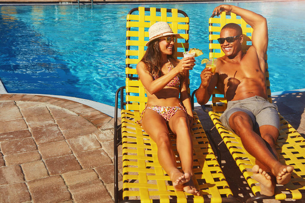 Ar fresco e sol. Tiro de ângulo alto de um jovem casal afetuoso desfrutando de algumas bebidas à beira da piscina - Foto, Imagem