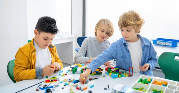 Robot programlama dersi. Çocuklar robot yapıp kodluyorlar. İnşaat blokları, dizüstü bilgisayar ve uzaktan kumandalı joystick kullanarak STEM eğitimi. Okul çocukları için teknolojik eğitim gelişimi - Fotoğraf, Görsel