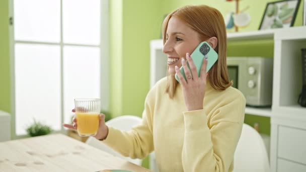 Fiatal szőke nő beszél okostelefonon iszik narancslevet otthon - Felvétel, videó