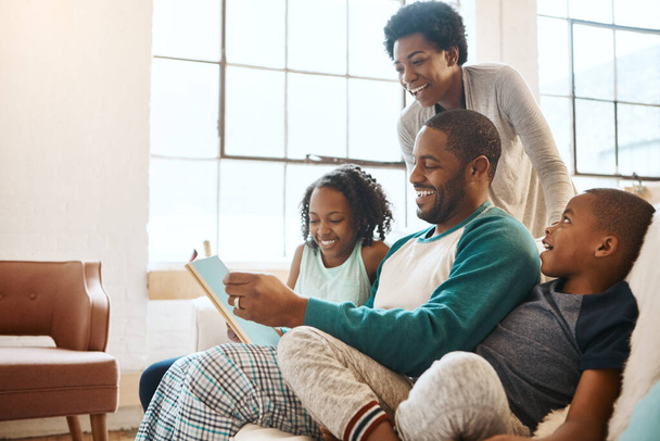 Quando você ensina seus filhos, você ensina seus filhos filhos. uma família lendo um livro dentro de casa - Foto, Imagem