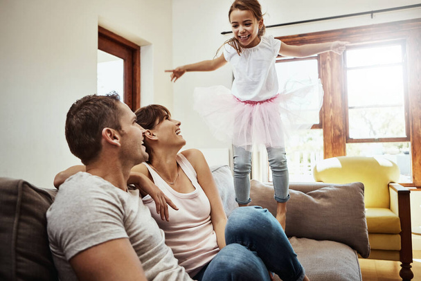 Etrafta çocuklar varken, eğlence her zaman garantilidir. Küçük bir kız evdeki ailesiyle bağ kurarken kanepeye atlıyor. - Fotoğraf, Görsel