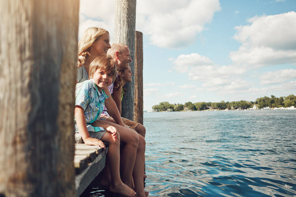 Adoro legare con la mia meravigliosa famiglia. una giovane famiglia su un molo mentre fuori sul lago - Foto, immagini