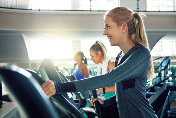Make it a great day by going to the gym. a young woman working out with a machine at a gym - Foto, Imagem