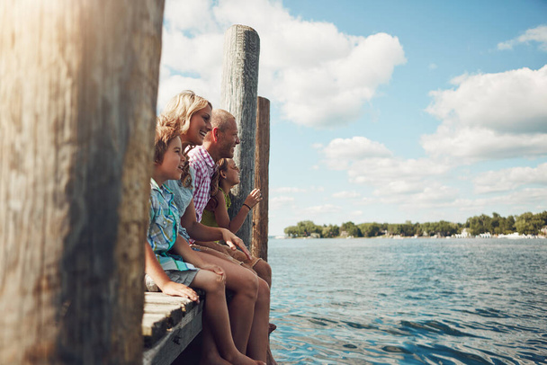 La famille est une grande aventure. une jeune famille sur une jetée au bord du lac - Photo, image