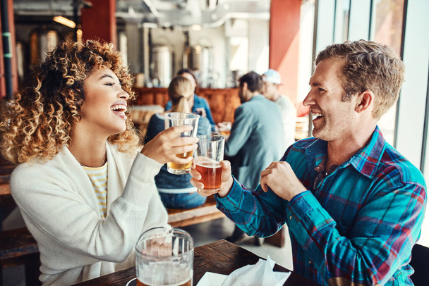 Είναι το είδος του κοριτσιού που μπορείς να πας στο μπαρ. ένα νεαρό ζευγάρι που πίνει ποτά σε ένα μπαρ με ανθρώπους θολή στο παρασκήνιο - Φωτογραφία, εικόνα