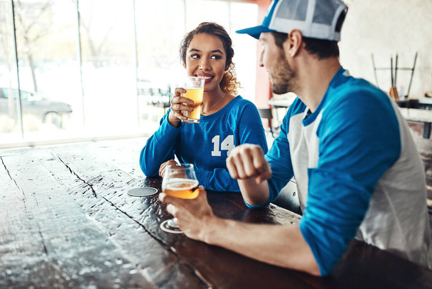 Dates du jour du match. un jeune homme et une jeune femme qui boivent des bières en regardant un match de sport dans un bar - Photo, image