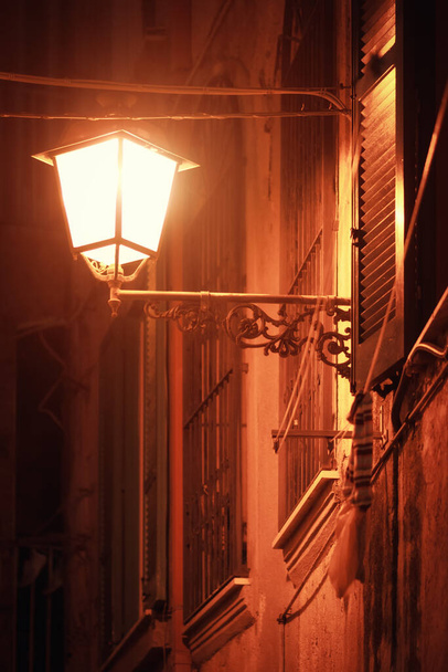 Straßenlaterne in der Nacht. Beleuchtung einer alten Straße in Italien. Helle Lampe an der Stadtmauer. - Foto, Bild