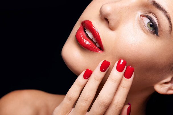 Beauty, makeup and woman with red lipstick and nails in a studio with a self care pamper treatment. Cosmetic, portrait and half face closeup of female model with a facial routine by black background - Zdjęcie, obraz