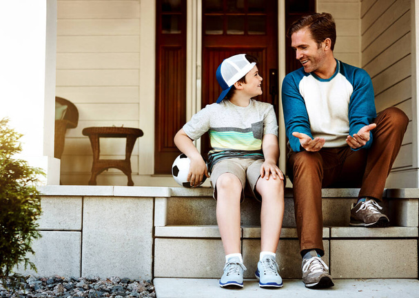 Teaching him the rules of soccer. a father and his son bonding on their porch at home - Foto, afbeelding