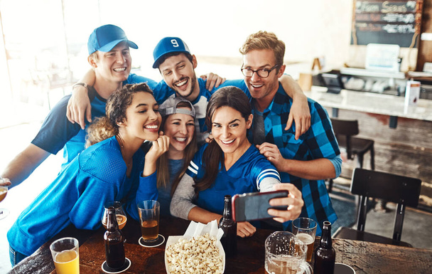 Quand son jour de jeu, vous devez prendre un selfie. un groupe d'amis prenant un selfie tout en regardant un jeu de sport dans un bar - Photo, image