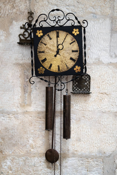 Old metallic pendulum clock on the white stone wall - Foto, afbeelding