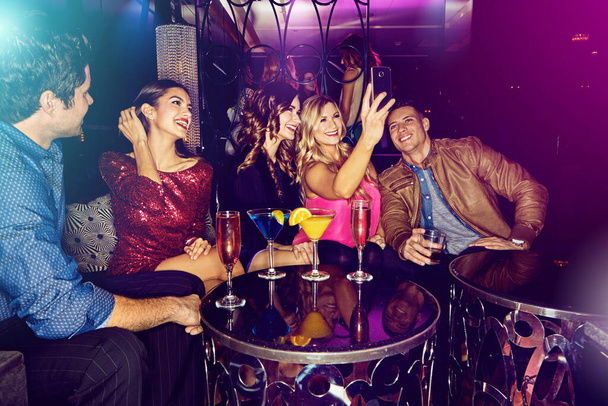 Llenando su teléfono con selfies divertidos. un grupo de amigos tomando selfies en un teléfono móvil en una discoteca - Foto, Imagen