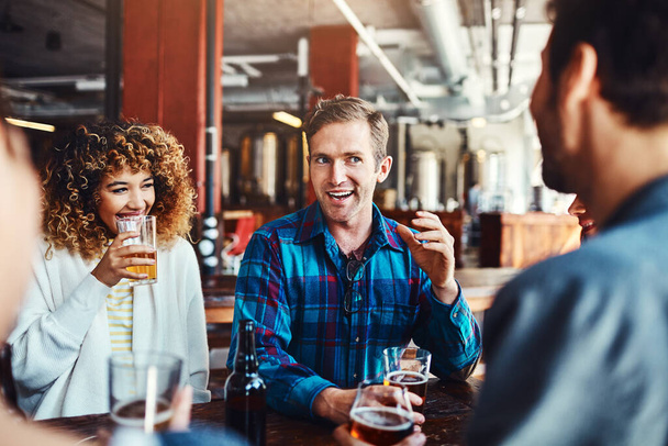 冷たいものを男たちと一緒につかむ。バーでビールを楽しんでいる友人たちが - 写真・画像