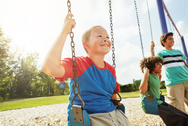 Jeu gratuit en plein air est bénéfique pour les enfants. jeunes garçons jouant sur les balançoires au parc - Photo, image