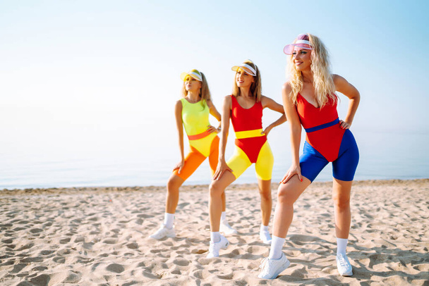 Young dancers in colorful swimsuits are dancing in the morning. oncept of sports, fitness, aerobics. Active sport. - Фото, зображення