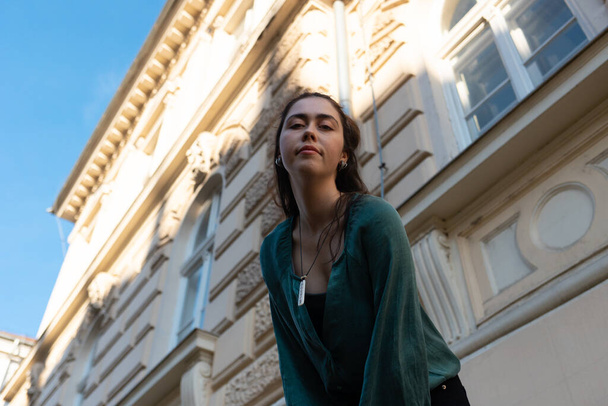 Unterseite Ansicht der jungen lächelnden kaukasischen Frau posiert in der Nähe von schönen Gebäude an der Straße. Konzept von Psychologie und Urlaub. - Foto, Bild
