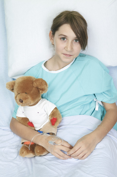 Little girl in hospital bed with teddy bear - Фото, зображення