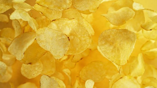 Potatoes chips flying up in the air. Fly junk food isolated on yellow background. - Foto, immagini