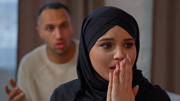 Pár veszekedés szomorú síró muszlim nő felesége ül a kanapén sikoltozó férj vádolja feleségét. Szakítás házasság válás nem kívánt terhesség féltékeny dühös afro-amerikai férfi visszaélés vitatkozó családi konfliktus - Fotó, kép