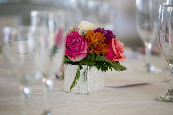This captivating image showcases the elegant decor and stunning floral arrangements of a real wedding. The photograph features a beautifully decorated table in a charming wedding venue, adorned with delicate flowers, candles, and other decorative ele - Foto, Imagen