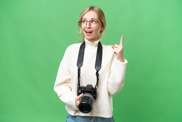 Giovane fotografo donna inglese su sfondo isolato puntando in alto e sorpreso - Foto, immagini