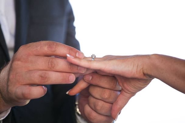 This beautiful image captures the intimate moment of a couple exchanging wedding rings at a real wedding. The photograph features a close-up of the couple's hands, showcasing their intertwined fingers and the wedding bands on their fingers. The image - Zdjęcie, obraz