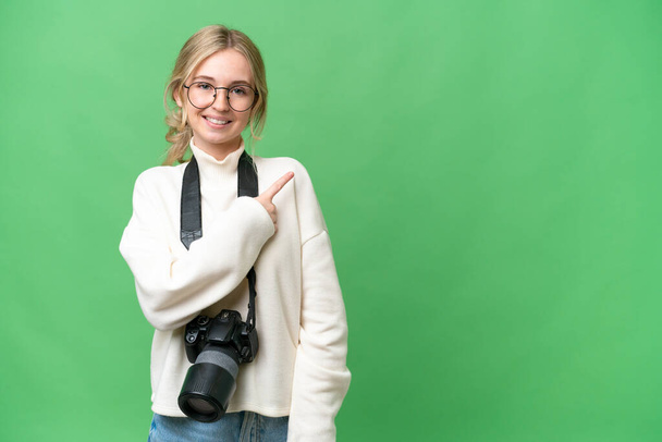 Młoda fotograf angielski kobieta na odosobnionym tle wskazując na stronie przedstawić produkt - Zdjęcie, obraz