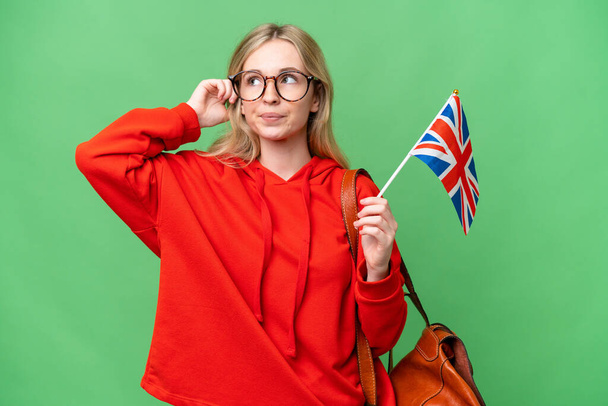 Young hispanic woman holding an United Kingdom flag over isolated background having doubts and thinking - Foto, Bild