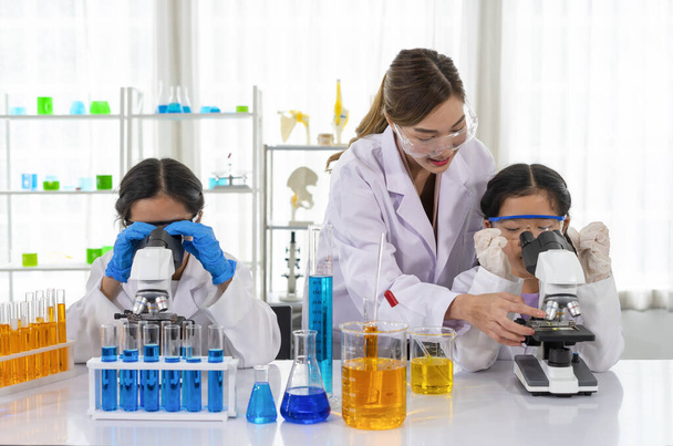 female scientist as a mentor is teaching the students, kids studying science in laboratory - Foto, Imagen