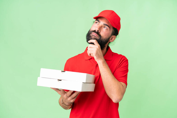 homem de entrega de pizza com uniforme de trabalho pegar caixas de pizza sobre fundo chave croma isolado e olhando para cima - Foto, Imagem