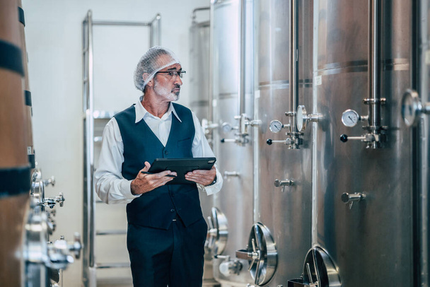Producent wina pracujący w nowoczesnej fabryce dużych napojów likierowych przemysł jakości i monitorowania fermentacji - Zdjęcie, obraz