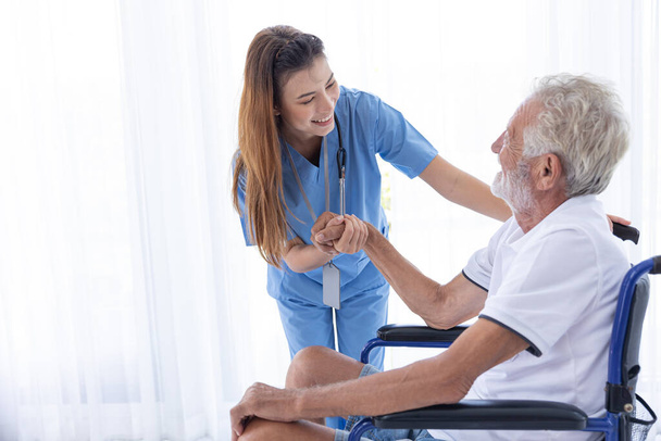 Opieka domowa pielęgniarka personel dbać starszy mężczyzna siedzi na wózku inwalidzkim szczęśliwy uśmiech razem w domu. - Zdjęcie, obraz