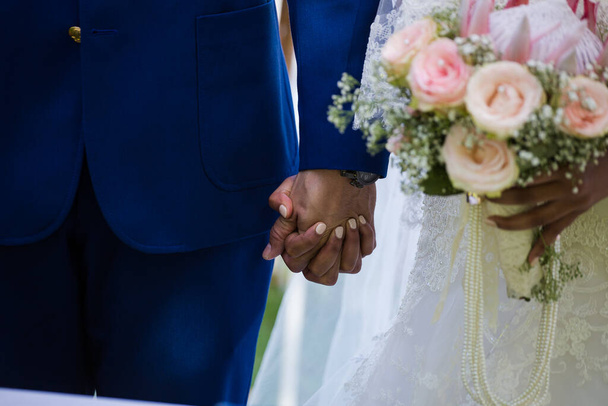 This beautiful image captures the intimate moment of a couple exchanging wedding rings at a real wedding. The photograph features a close-up of the couple's hands, showcasing their intertwined fingers and the wedding bands on their fingers. The image - Φωτογραφία, εικόνα