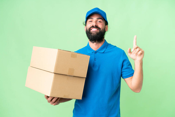 Delivery caucasian man over isolated chroma key background showing and lifting a finger in sign of the best - Photo, Image