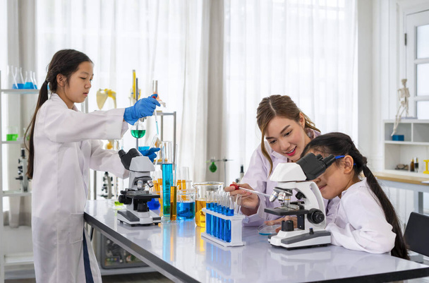 Женщина-ученый в качестве наставника учит студентов, детей, изучающих науку в лаборатории - Фото, изображение