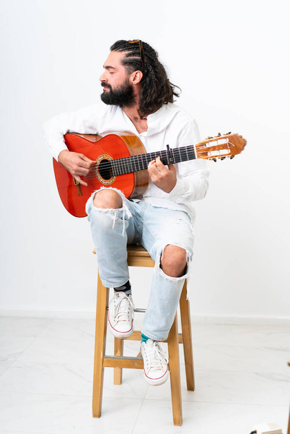 Young man with beard playing guitar on white background - Fotoğraf, Görsel