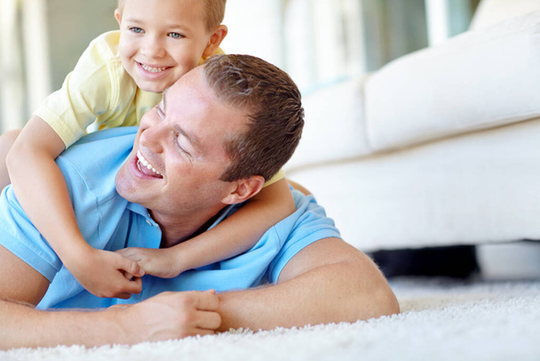 Got you, dad. Young boy and his father wrestling playfully in the lounge - Фото, зображення