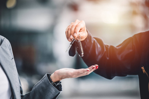 Closeup male hand giving a car key for vehicle loan credit financial, lease or rental concept - Foto, imagen