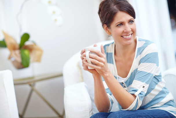 Enjoying a cup of comfort. a beautiful woman enjoying a cup of coffee at home - Zdjęcie, obraz