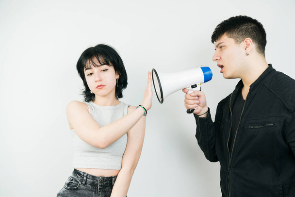 νεαρός άνδρας που φωνάζει με μεγάφωνο και γυναίκα που δείχνει πινακίδα στοπ - Φωτογραφία, εικόνα