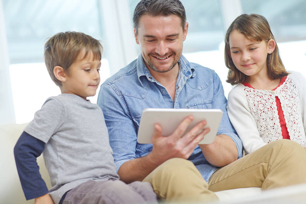 Навчання своїх дітей технологіям. люблячий батько використовує цифровий планшет зі своїм сином і дочкою вдома
 - Фото, зображення