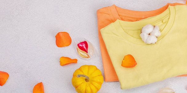 Οικολογικός καθαρισμός ανοιξιάτικης ντουλάπας, κάψουλες για πλύσιμο στο πλυντήριο. Pastel χρωματιστά T-shirts μωρό, έννοια της πώλησης. Κάθετη αποθήκευση ενδυμάτων. Ελαφρύ πέτρινο φόντο από μπετόν - Φωτογραφία, εικόνα