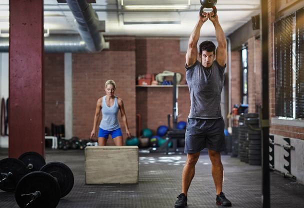 Theyre making this workout count. two people working out with kettlebells in a gym - Foto, immagini