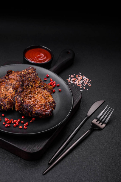 Délicieux steak de bœuf ou de porc sur l'os grillé avec des épices et du romarin sur un fond de béton foncé - Photo, image