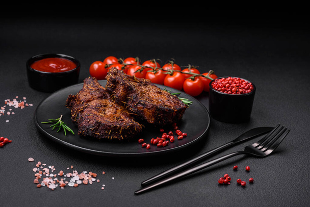 Delicious beef or pork steak on the bone grilled with spices and rosemary on a dark concrete background - Photo, Image