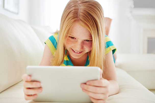Learning the modern way. a little girl using a digital tablet at home - Foto, Bild