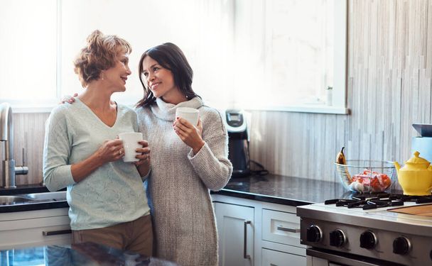 Tus visitas significan mucho para mí, mamá. una joven disfrutando de una pausa para tomar un café y charlar en la cocina con su madre en casa - Foto, Imagen