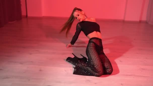Seductive female in top dance and dance pants is dancing on the floor of red lighted studio room. High quality FullHD footage - Footage, Video