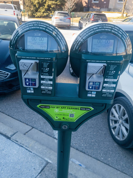 Zielony parkometr w Birmingham, MI pokazuje upływ czasu. Samochody są zaparkowane przy liczniku.. - Zdjęcie, obraz